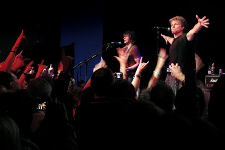 Valokuva Bon Jovin yllätyskeikalta Lontoossa. Hämärässä valaistuksessa lauma muusikoita suuren yleisömeren edessä.